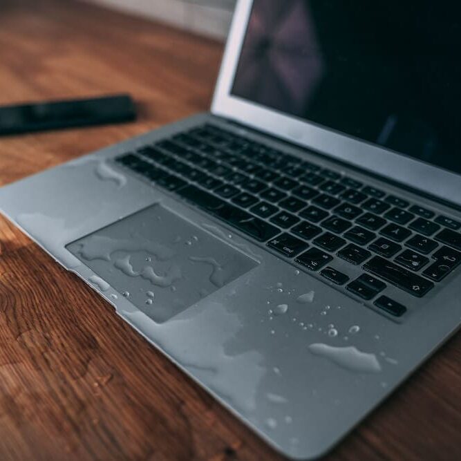 AdobeStock_290814391-1 Water from a glass spilled on laptop