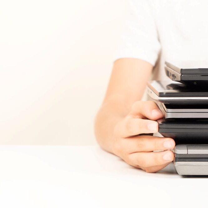 A woman holding her old laptops and getting them ready for a laptop trade-in.