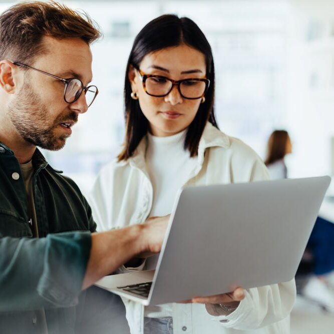 Business professionals using a laptop together in an office.