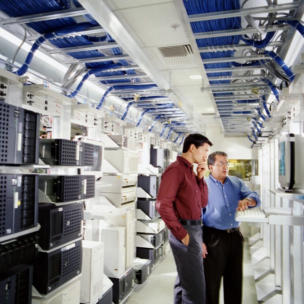 Two Men Looking at Drives & Working Inside of Data Center